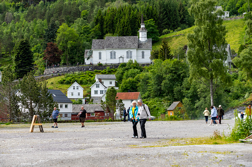 Hellesylt in Norway including the famous white church that most tourists and cruise ship passengers visit.  In the foreground are some of those cruise passengers.