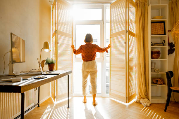 istock Woman opens window blinds at sunny room 1424661700