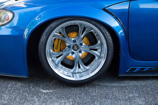 Front wheel and rim  of very deep laid blue car with huge wheels and tires parked in street of residential district in Bangkok Chatuchak