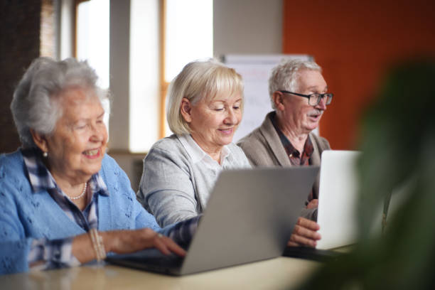 Senior group in retirement home learning together in computer class stock photo