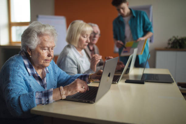 istock Senior group in retirement home with young instructor learning together in computer class 1424663840