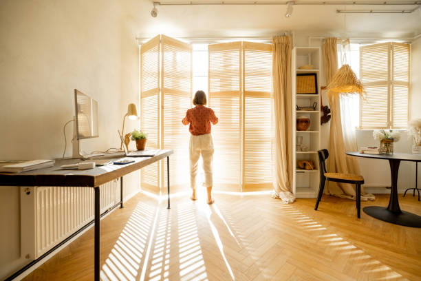 istock Woman opens window blinds at sunny room 1424663947