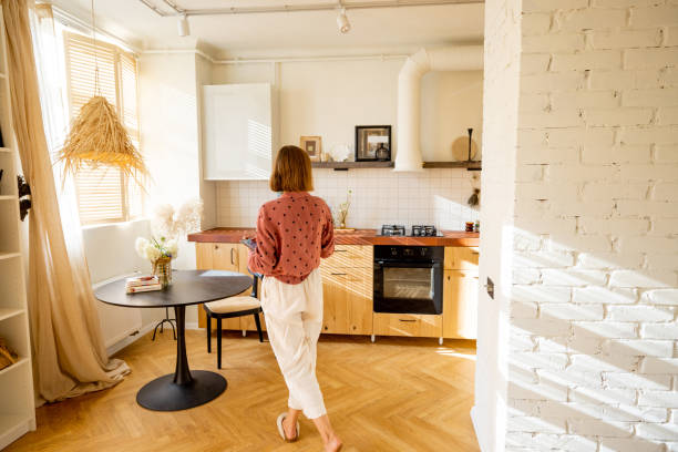 istock Woman puts flowers on a dinner table at sunny apartment 1424664579