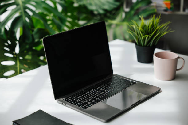 istock Laptop, note book and a cup on work desk in workplace with ornamental plant. 1424666215