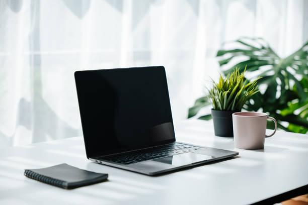 istock Laptop, note book and a cup on work desk in workplace with ornamental plant. 1424666362