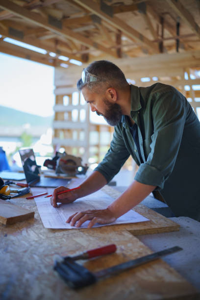 istock Construction worker smiling, drawing and checking blueprints, diy eco-friendly homes concept. 1424666424