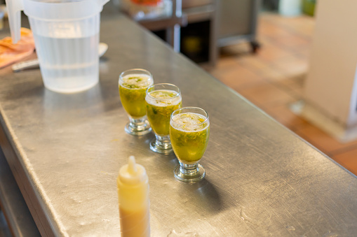 latino man employee of a small restaurant prepares delicious lulada typical colombian dessert that he serves in a glass cup to present to his clients