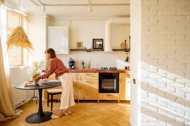 istock Woman puts flowers on a dinner table at sunny apartment 1424668621