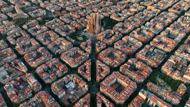 vue aérienne des toits de la ville de barcelone et de la cathédrale de la sagrada familia au lever du soleil. eixample résidentiel célèbre réseau urbain. paysage urbain avec des blocs d’octogone urbains typiques. catalogne, espagne - barcelone espagne photos et images de collection