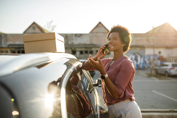 istock Woman standing by her car, gesturing while talking on the phone with a friend 1424669441
