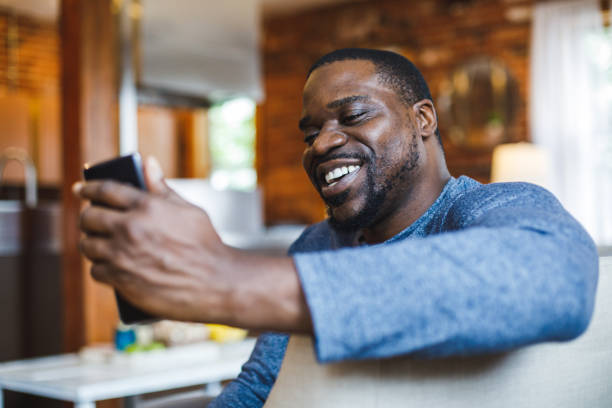 istock Man smiling at front facing camera on smart phone while video chatting with a friend 1424671135