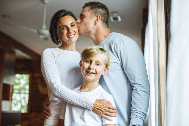istock Boy smiling at camera while his loving parents are embracing him 1424671333