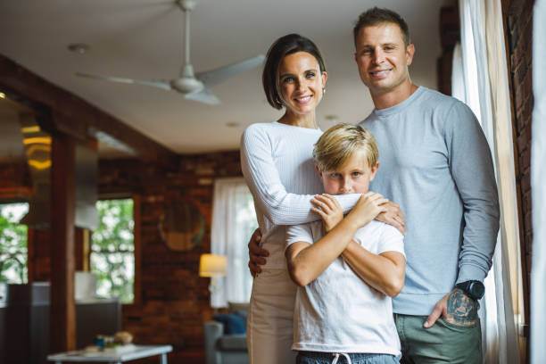 istock Boy and his parents standing embraced, looking at camera and smiling 1424671339