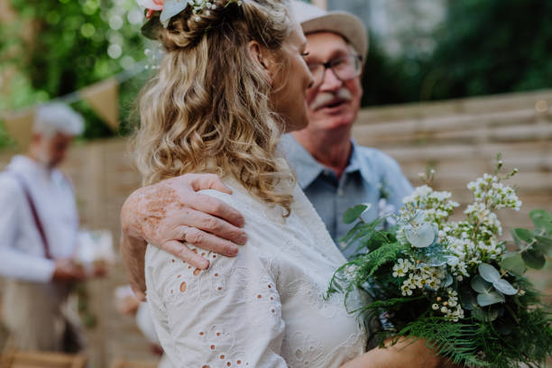 istock Mature bride receiving congratulations at wedding reception outside in the backyard. 1424672043