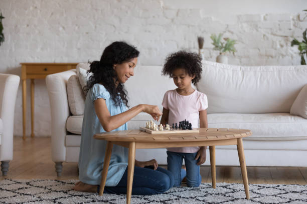 giovane madre africana e piccola figlia giocano a scacchi - concentration chess playing playful foto e immagini stock