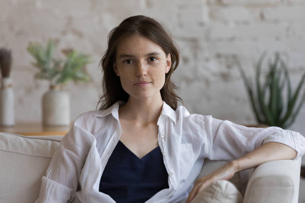istock Headshot portrait serious woman pose on camera seated on sofa 1424679281