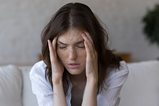 Mujer pecosa toca sienes sufre de dolor de cabeza se siente poco saludable, primer plano photo