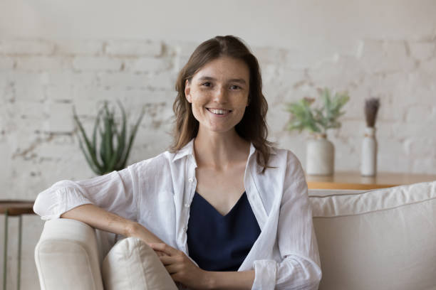 istock Pretty freckled woman sit on sofa smile staring at camera 1424679623