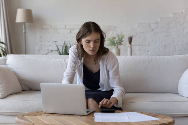 istock Young woman manage finances using calculator, pay bills online 1424679966