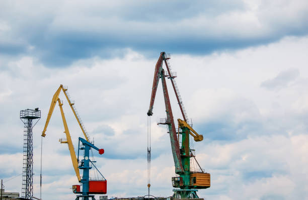 istock Large tower cranes stand in a river port against a cloudy sky. 1424680369