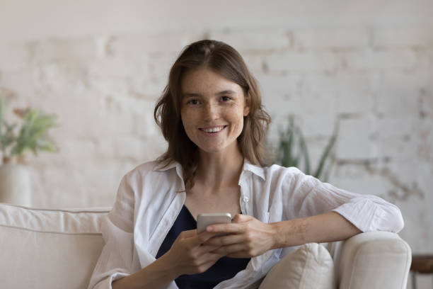 istock Attractive woman sit on sofa with modern smartphone 1424680437