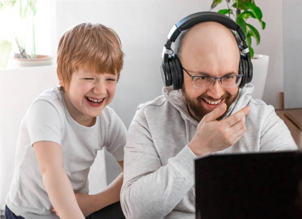 istock Dad and son smiling having fun talking at video chat look at the laptop screen 1424688960
