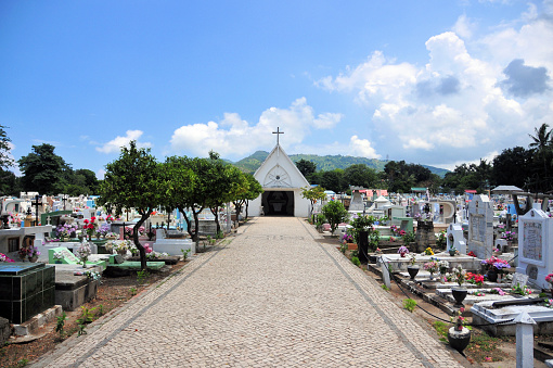 Dili, East Timor / Timor Leste: Santa Cruz cemetery, (in) famous for the 1991 massacre during the Indonesian occupation. The Santa Cruz massacre (also known as the Dili massacre) was the murder of at least 250 East Timorese pro-independence demonstrators - central lane with the mortuary chapel and Portuguese calçada pavement.