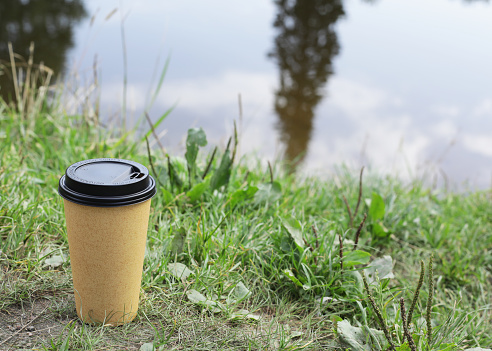 paper cup for coffee or tea, in nature on the background of the lake
