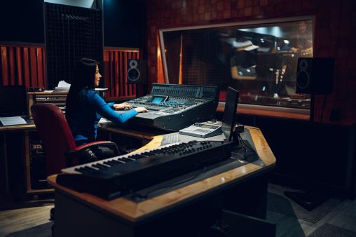 Mujer productora musical trabajando en una caja de resonancia de mezcla en un estudio. photo
