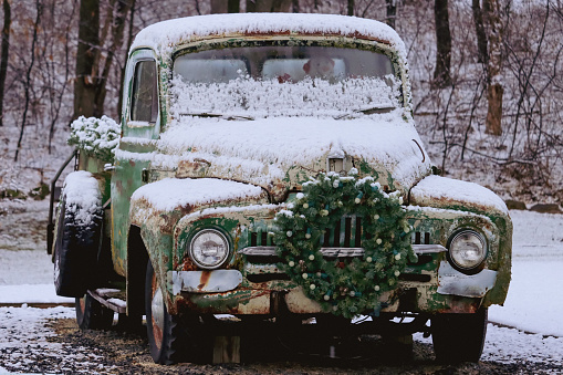 Vintage truck with Christmas wreath and snow man driving with snow on the car
