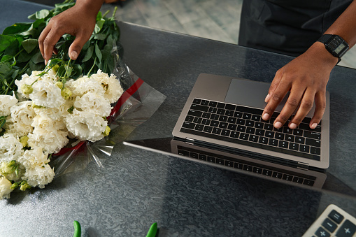 On the table lies a bouquet of flowers next to the laptop