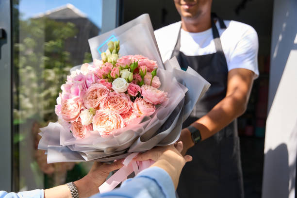 el comprador toma un hermoso ramo del vendedor - florist telephone flower business fotografías e imágenes de stock