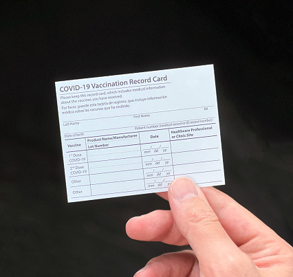 Blank COVID-19 vaccination record card being held by a person.