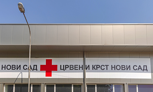 Novi Sad, Serbia - August 19, 2022: Long Banner Sign Red Cross Novi Sad Cyrillic Script at Office Building.
