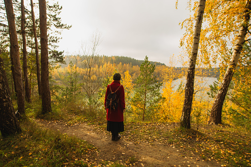 Redhead curly beautiful girl in coat in autumn forest. Pretty woman in turban enjoying vacation. Feel happiness. Charming smile. Happy lady