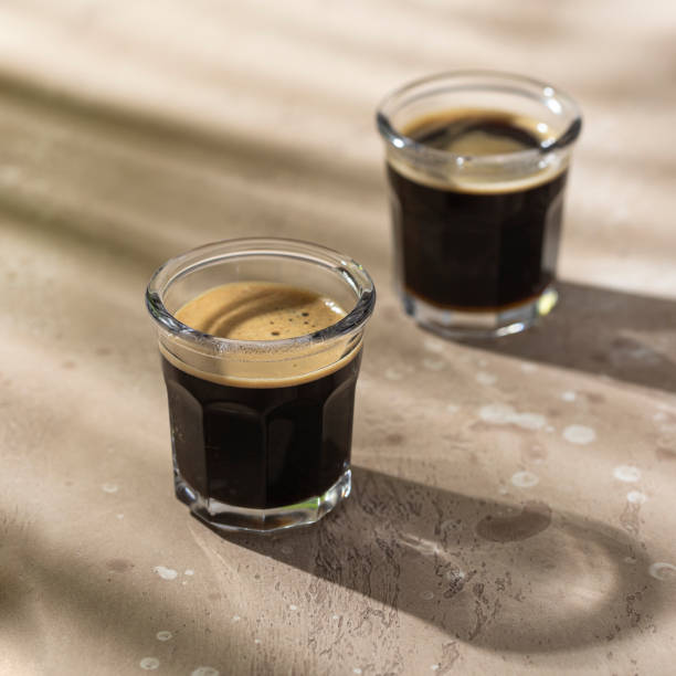 istock Two Espresso cups with foam on beige background with hard shadow. 1424746551
