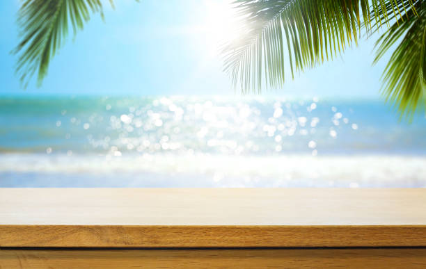 istock Empty wooden table over blurred sunny tropical beach background. Outdoor party mock up for design and product display. 1424747232