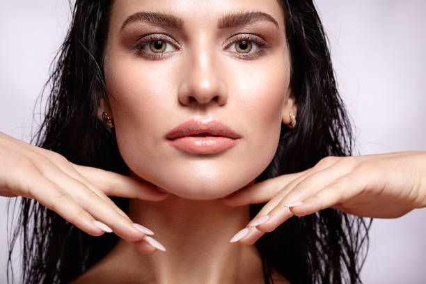 Portrait of a young brunette woman with shining wet make-up and shiny moist hair stock photo