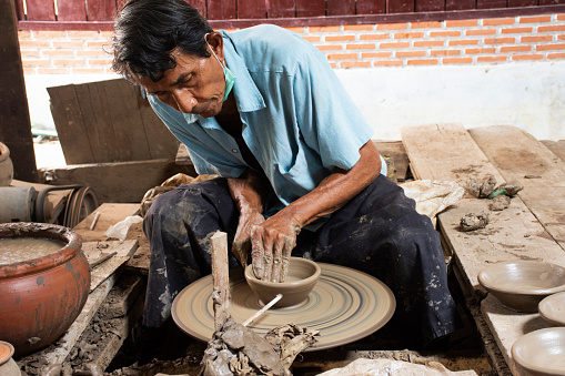 Thai craftsmanship technician or professional potter use machine work sculpture handmade pottery and handicraft earthenware in Koh Kret island at Pak Kret on September 3, 2022 in Nonthaburi, Thailand