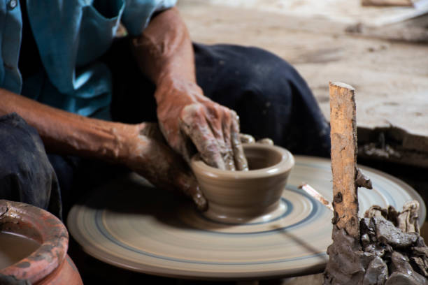 istock Thai craftsmanship technician or professional potter use machine working sculpture handmade pottery and handicraft earthenware for show sale at Koh Kret island in Pak Kret city at Nonthaburi, Thailand 1424769017