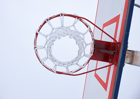 A close-up view of an Ice Hockey puck hitting the back of the goal net as shavings fly by, viewed from the front. Scoring a goal in ice hockey.