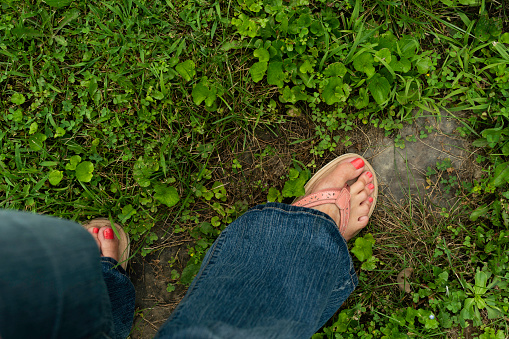 Partial view of barefeet in sandals walking on stone path in grass, West Virginia