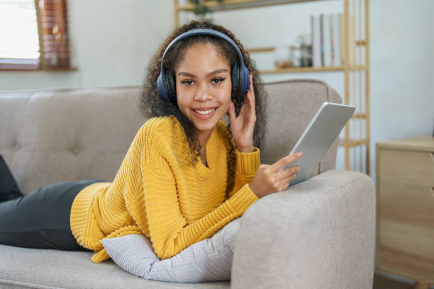istock frican American sitting on a sofa using tablet and wearing headphones to relax 1424802310