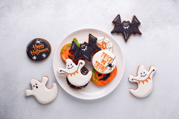 Halloween gingerbread cookies on white plate on stone background. Bright homemade cookies for Halloween party stock photo