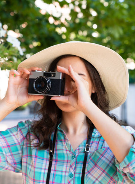 młoda kobieta trzyma analogową kamerę i patrzy przez wizjer - camera retro revival old fashioned holding zdjęcia i obrazy z banku zdjęć