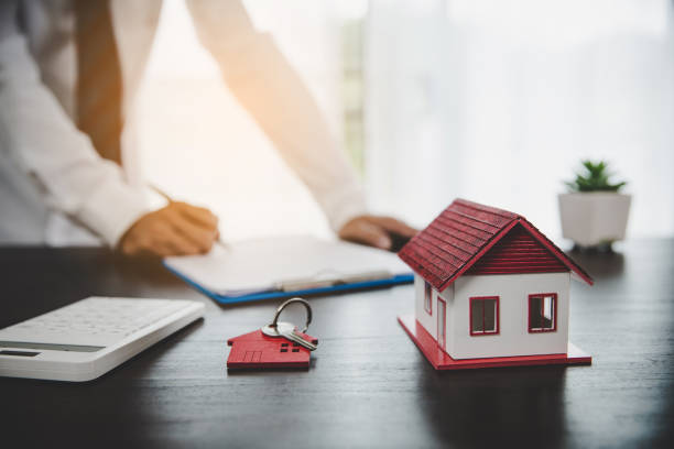 Real estate agents offer contracts to purchase or rent residential. Business person hands holding home model, small building red house. Mortgage property insurance moving home and real estate concept stock photo