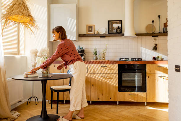istock Woman puts flowers on a dinner table at sunny apartment 1424832690