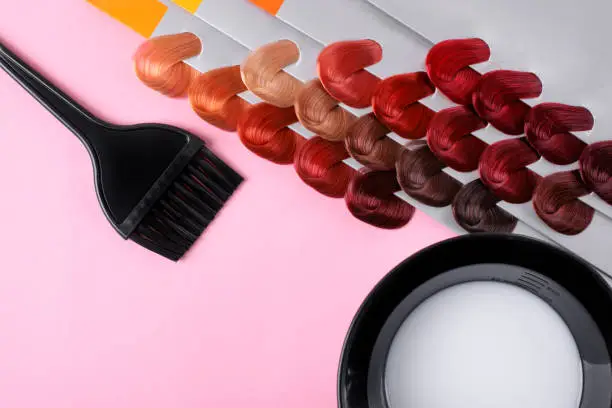 Photo of Professional hairdresser flat lay with hair dye swatches, applicator brush and mixing bowl