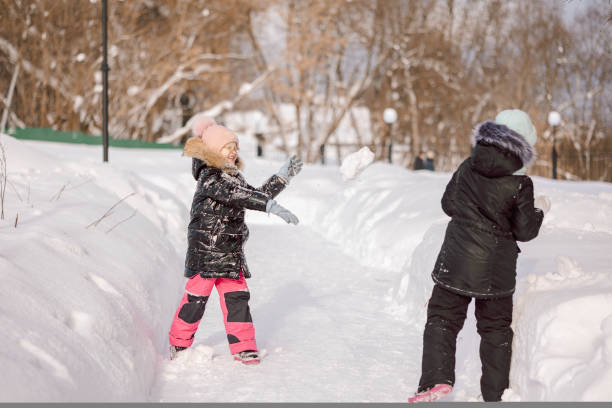meninas caminha ao ar livre no dia de inverno nevando no parque - playground snow winter little girls - fotografias e filmes do acervo