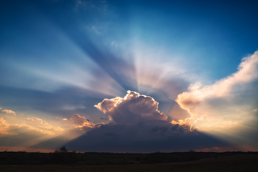 Beautiful sun beams in a sky over dramatic stormy clouds.